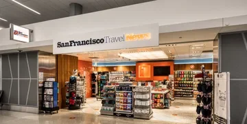 Entrance of San Francisco Travel News with shelves of snacks, drinks, travel accessories, and magazines displayed inside.