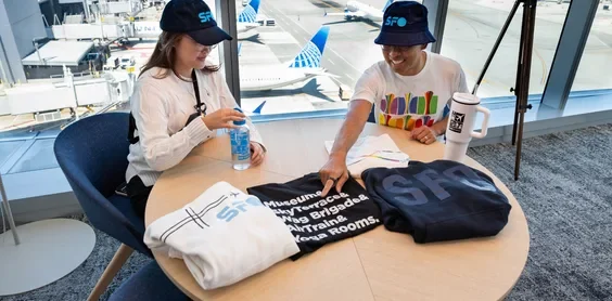 Two Airport staff seated at a table with SFO Gear products