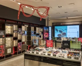 Designer sunglasses on display with artwork of red sunglasses at Sunglass Hut