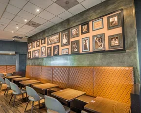 Seating area of 1300 on Fillmore at SFO with booths and portraits on the wall